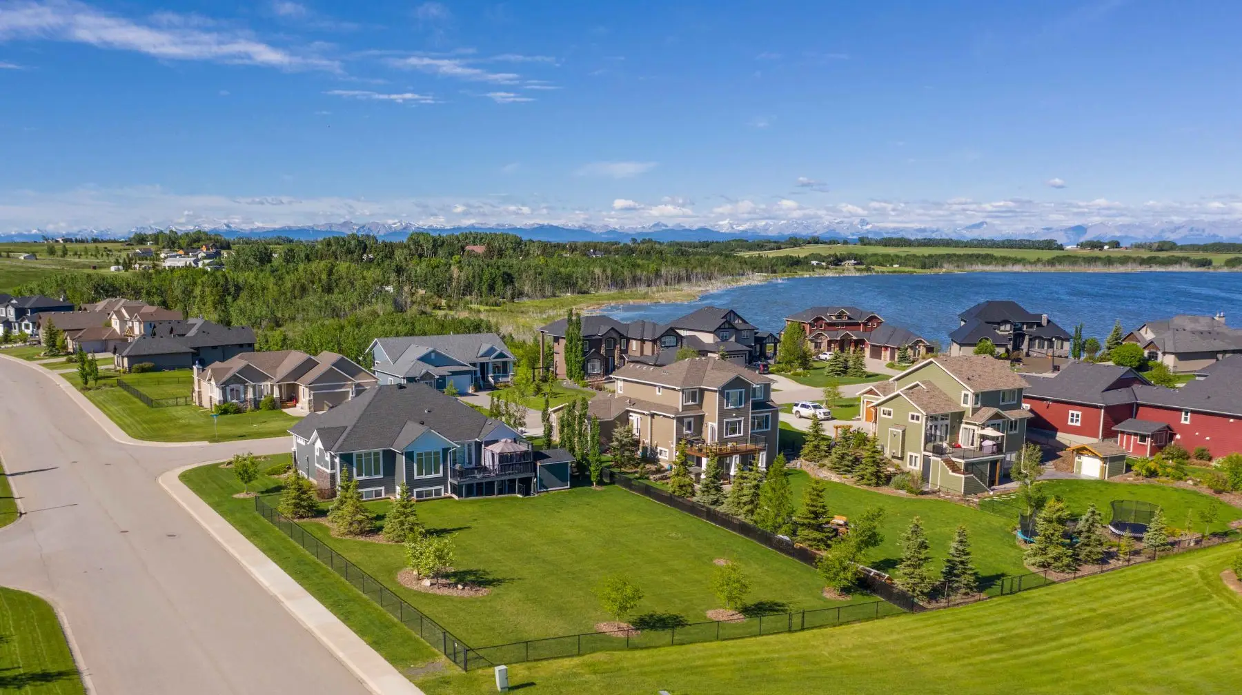 Aerial view of MonTerra, a lakeside estate community above Cochrane, Alberta, with the Rocky Mountains beyond
